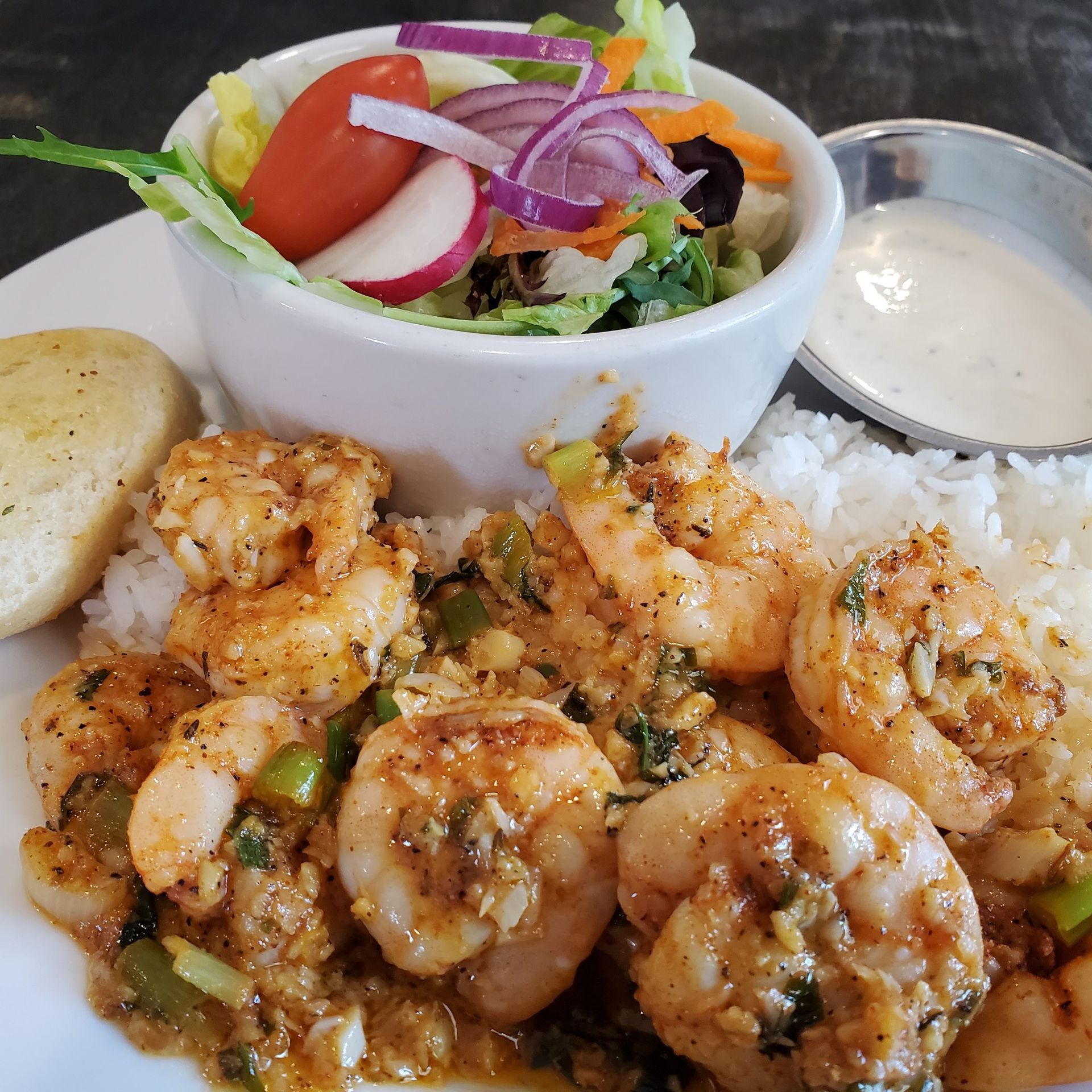 Shrimp scampi served with rice, salad, dressing, and bread.