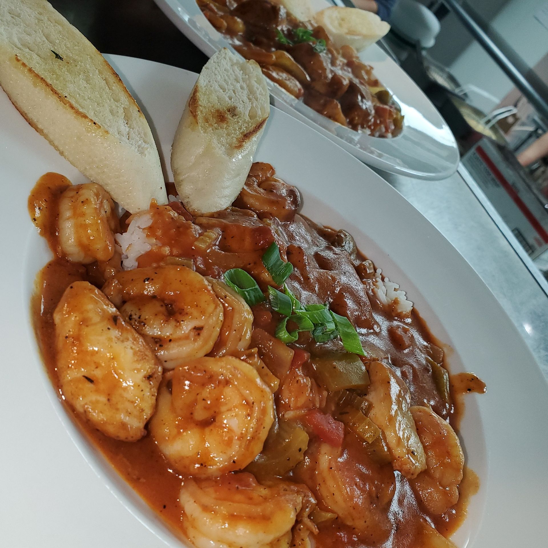 Shrimp etouffee over rice, with bread, and a second plate of food.