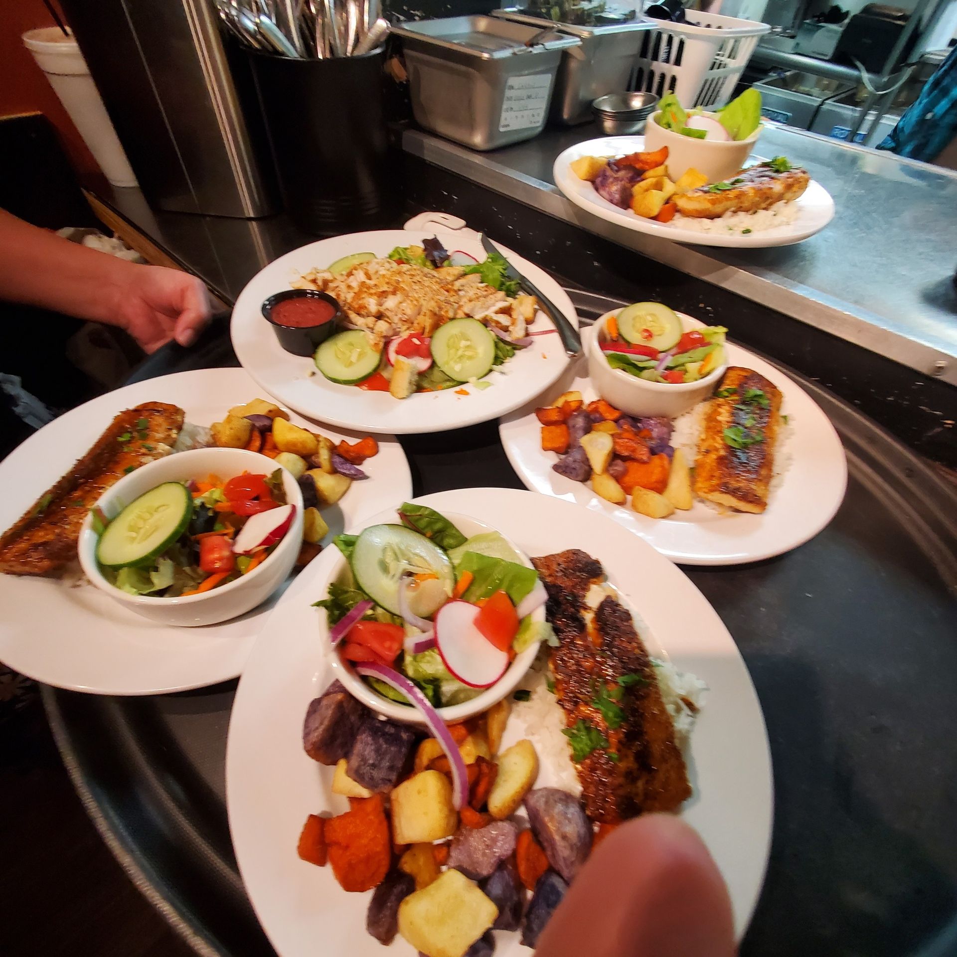 Plates of food on a counter: grilled fish, roasted vegetables, and salads.