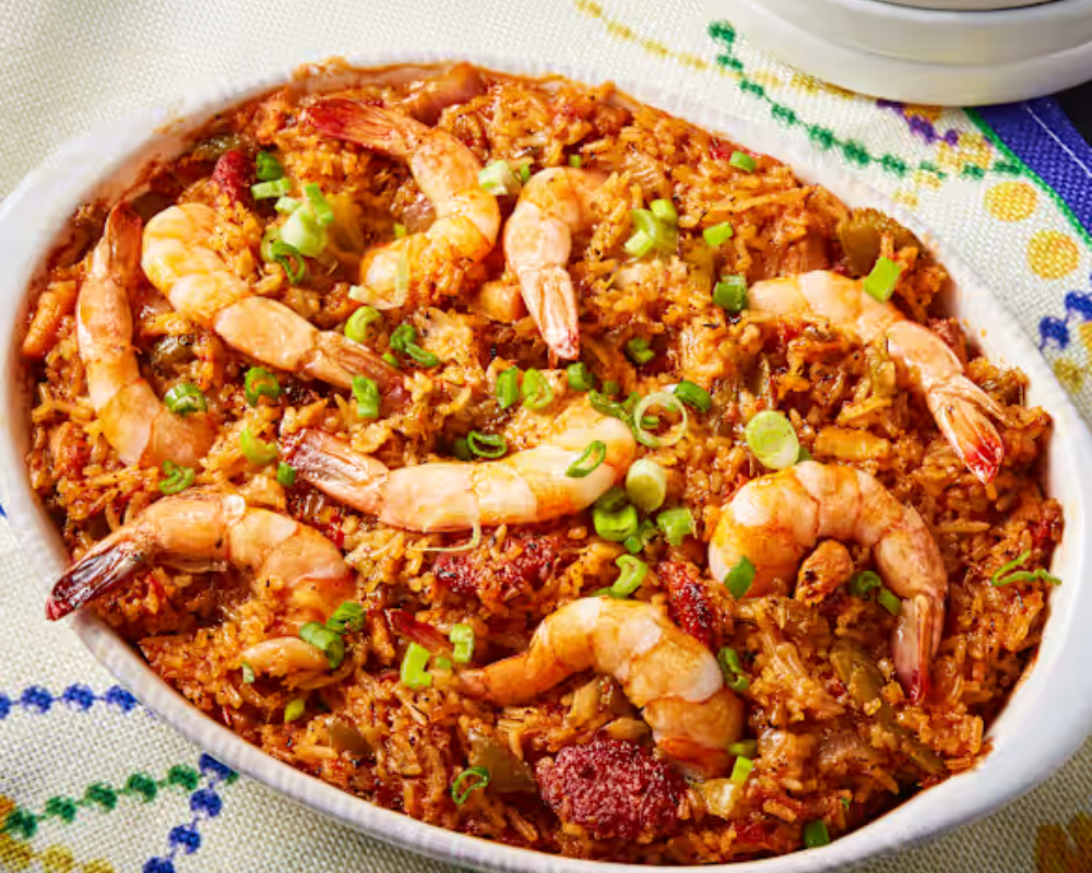 Shrimp jambalaya in a white oval baking dish, garnished with green onions.