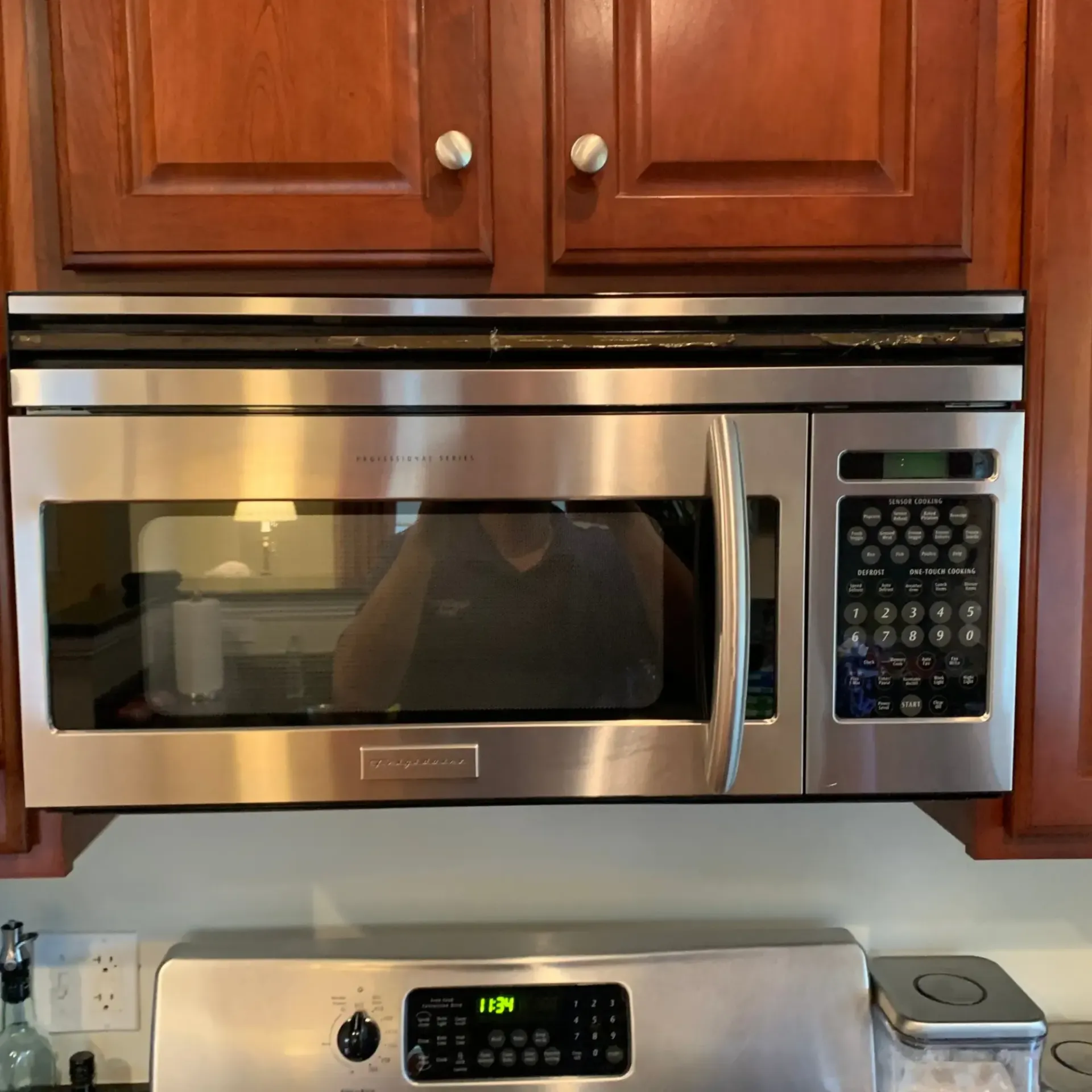 Appliance Tech- A stainless steel microwave oven with a reflection of a person in it