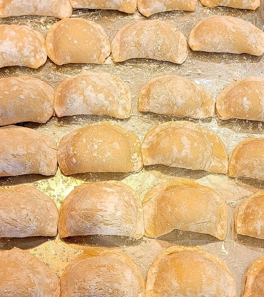 A bunch of pierogi are sitting on a tray on a table.