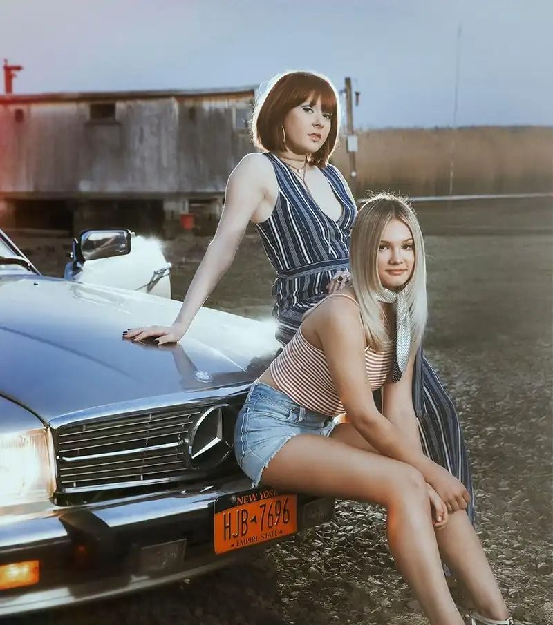 Two Beautiful Women Sitting on a Car