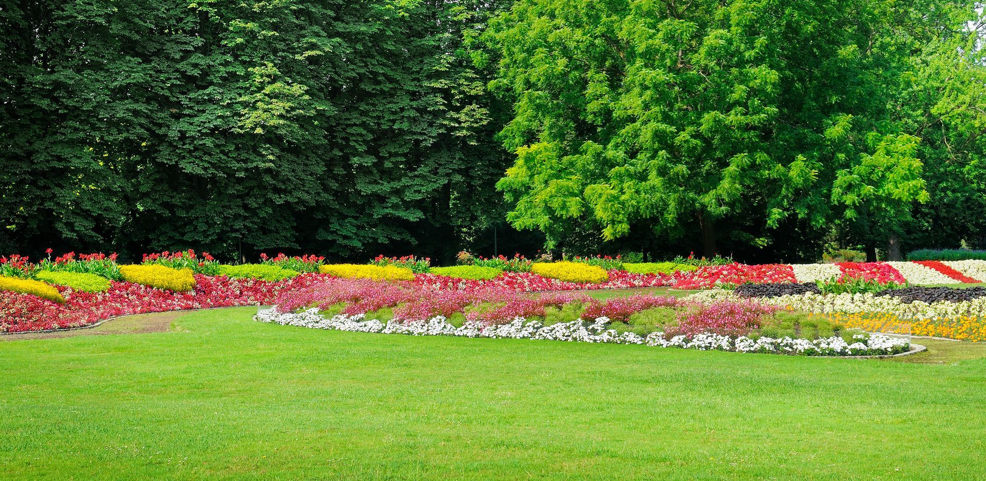Green lawn with colorful flower beds and trees.