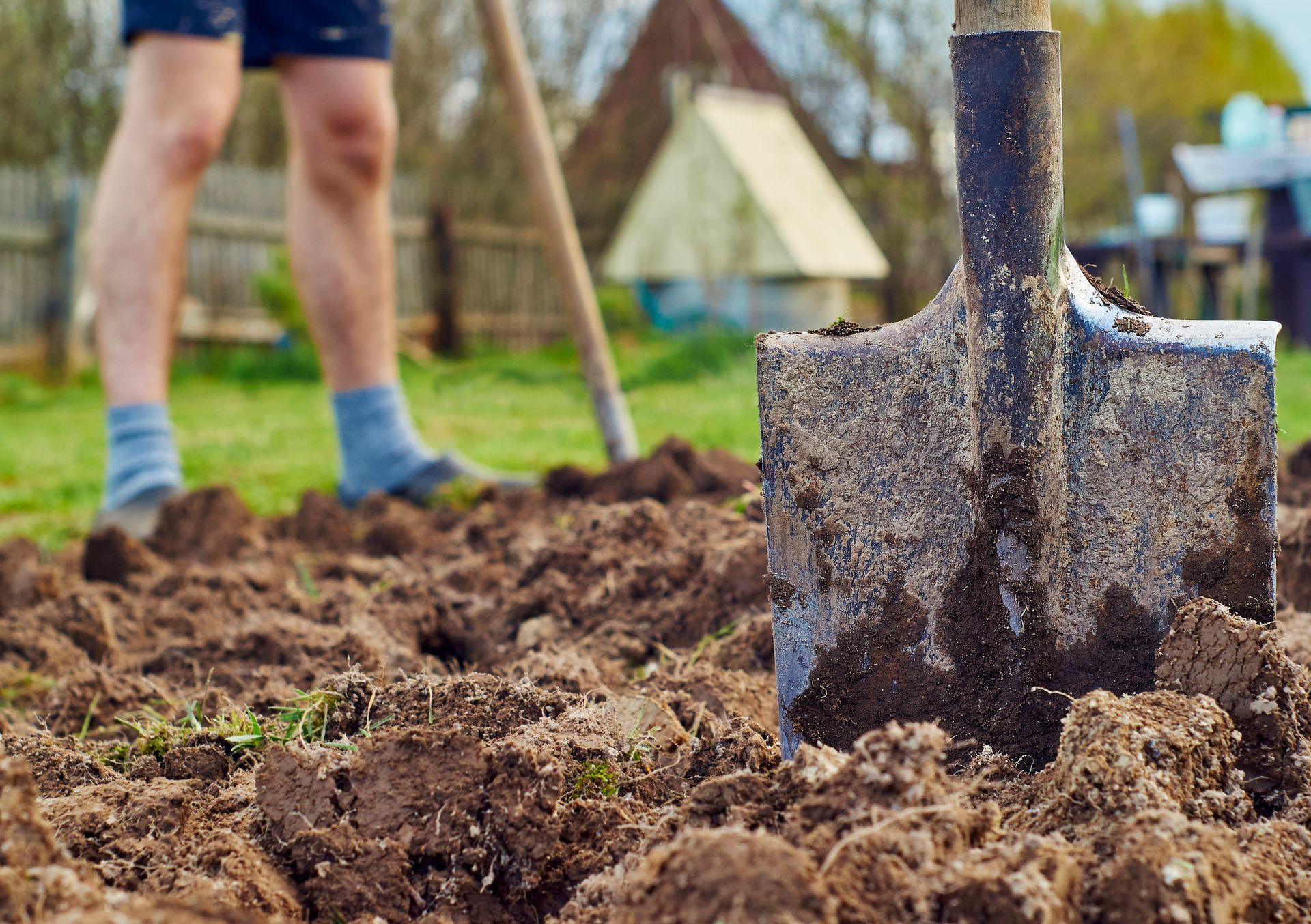 Person digging in a garden with a shovel; close-up on the shovel in the soil.