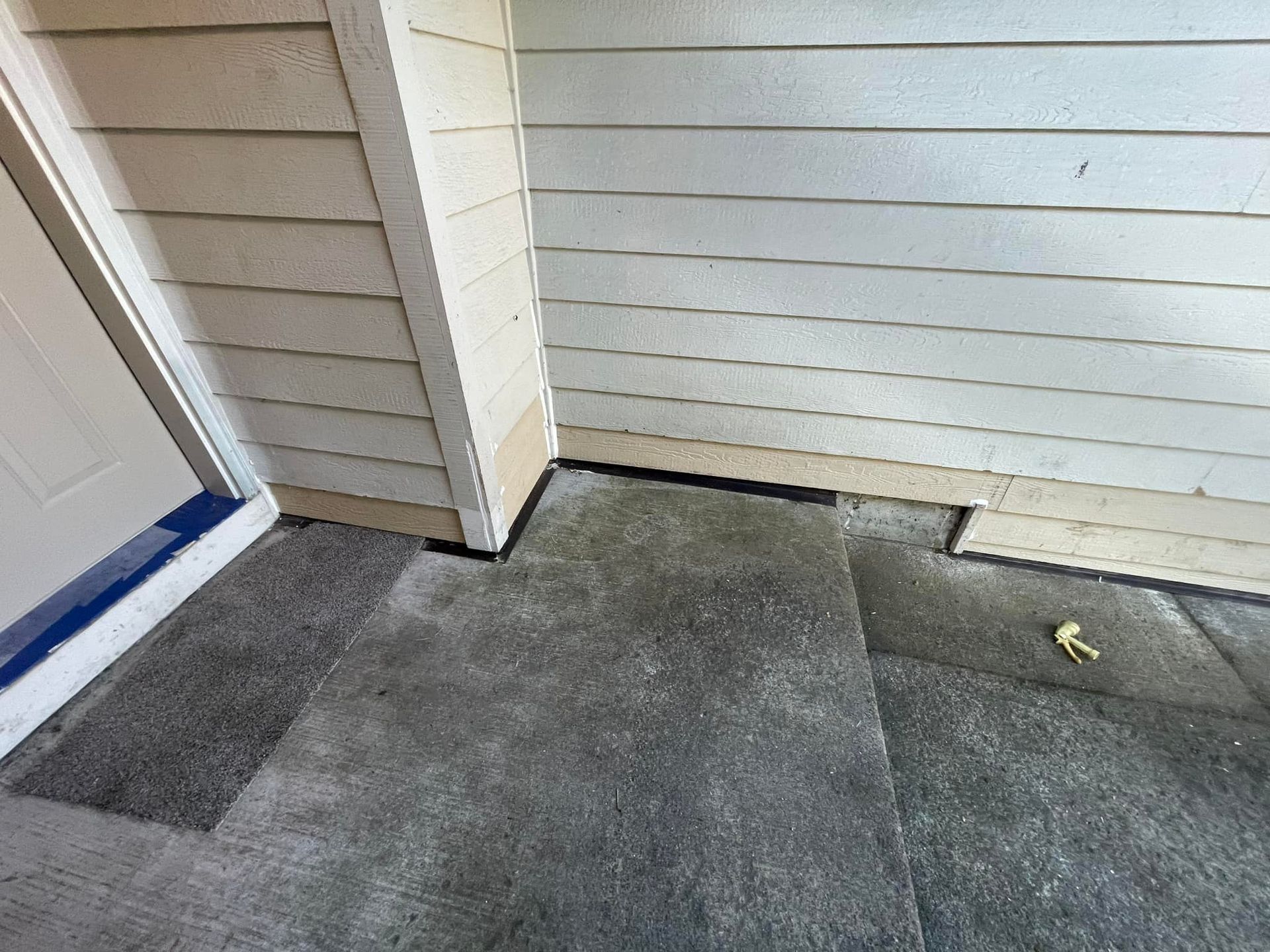 A corner of a house with a concrete floor and a door.