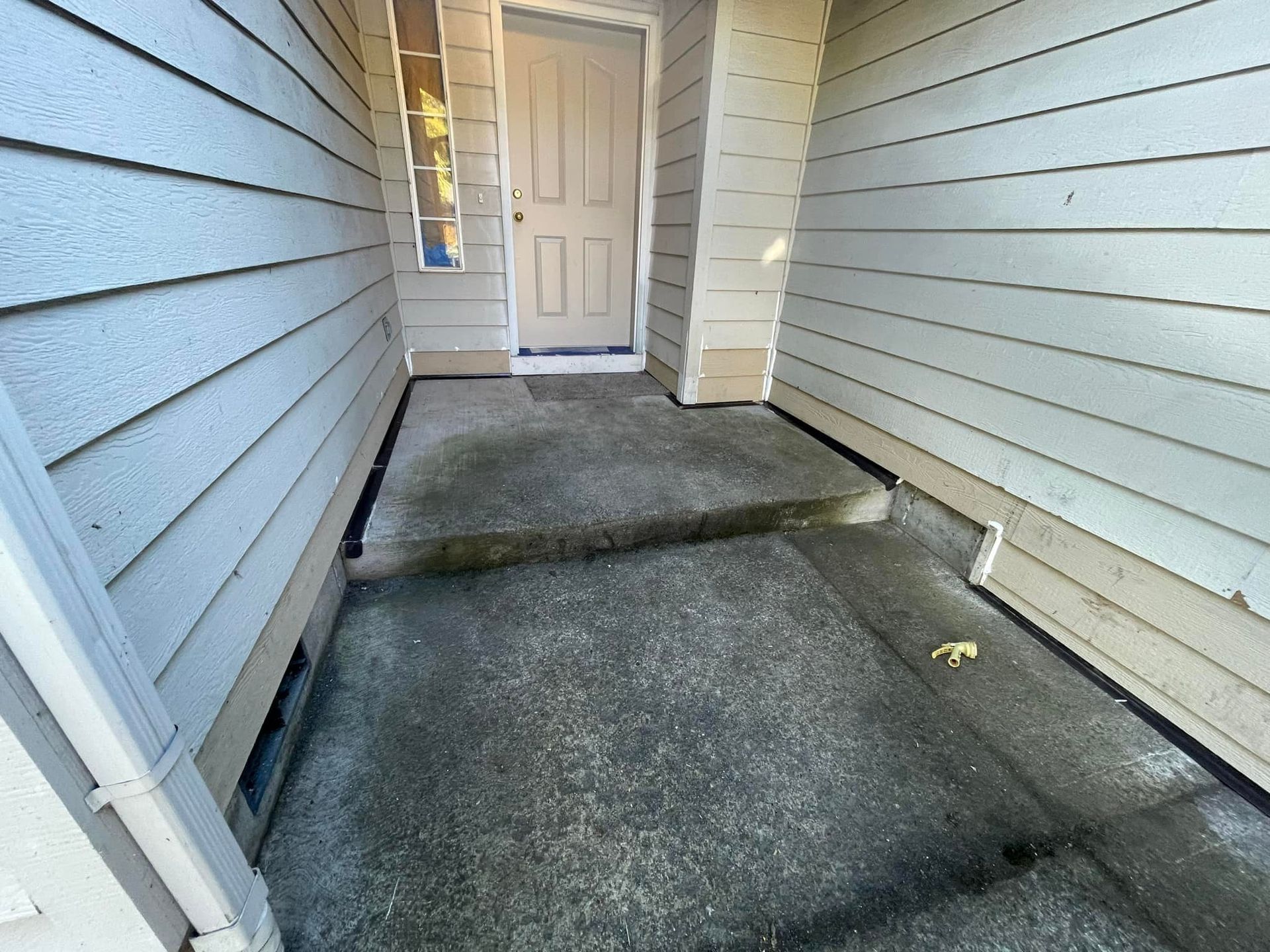 A concrete walkway leading to the front door of a house.
