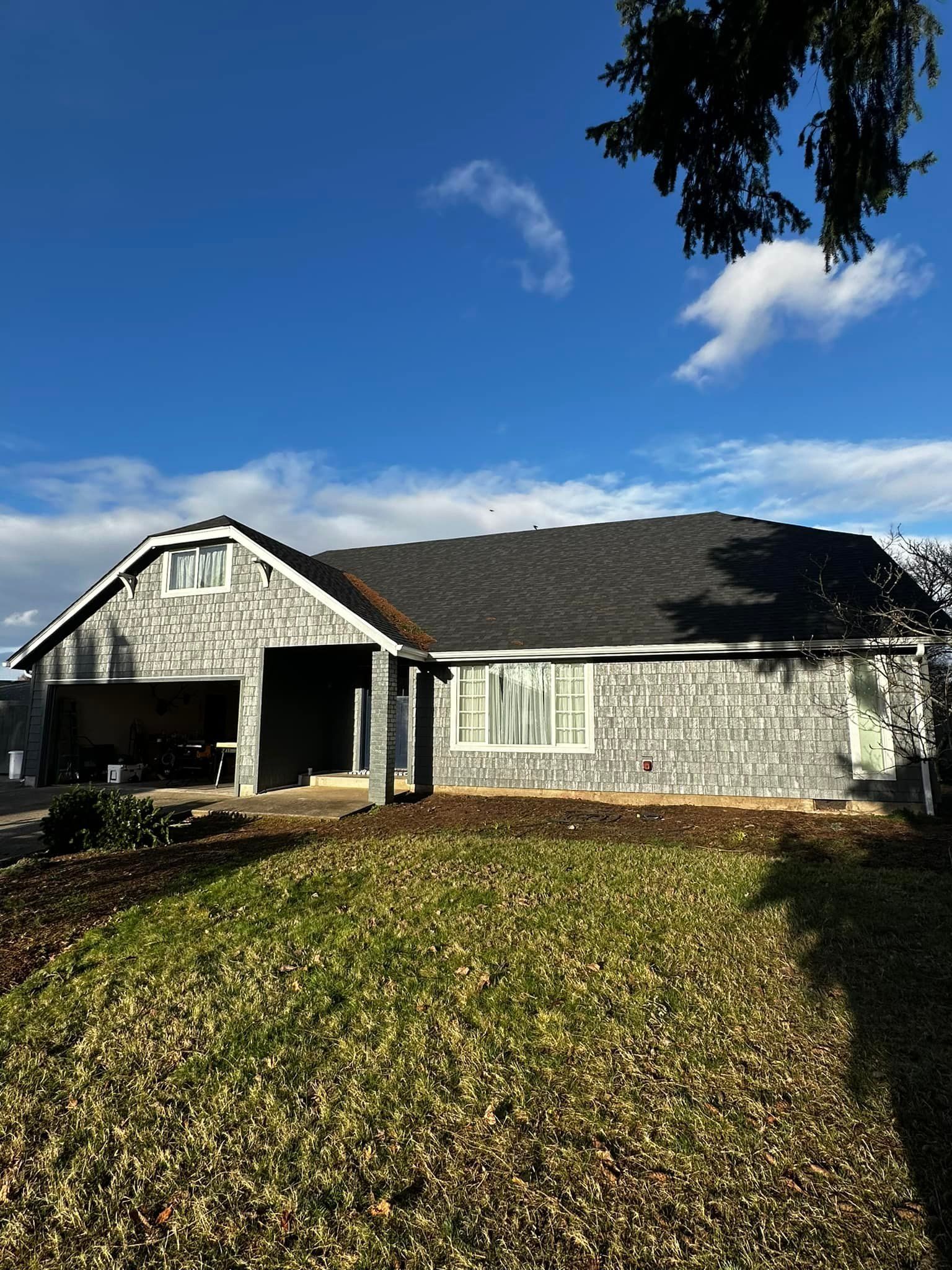 A house with a large lawn in front of it and a tree in the background.