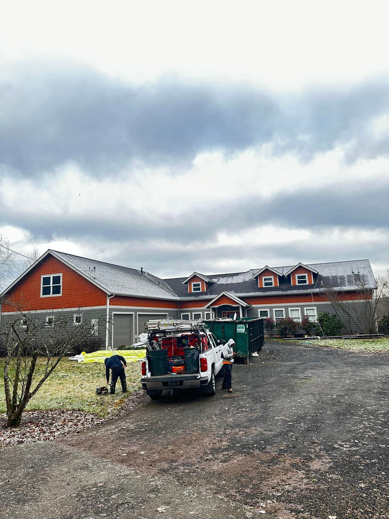 A truck is parked in front of a large house on a cloudy day.