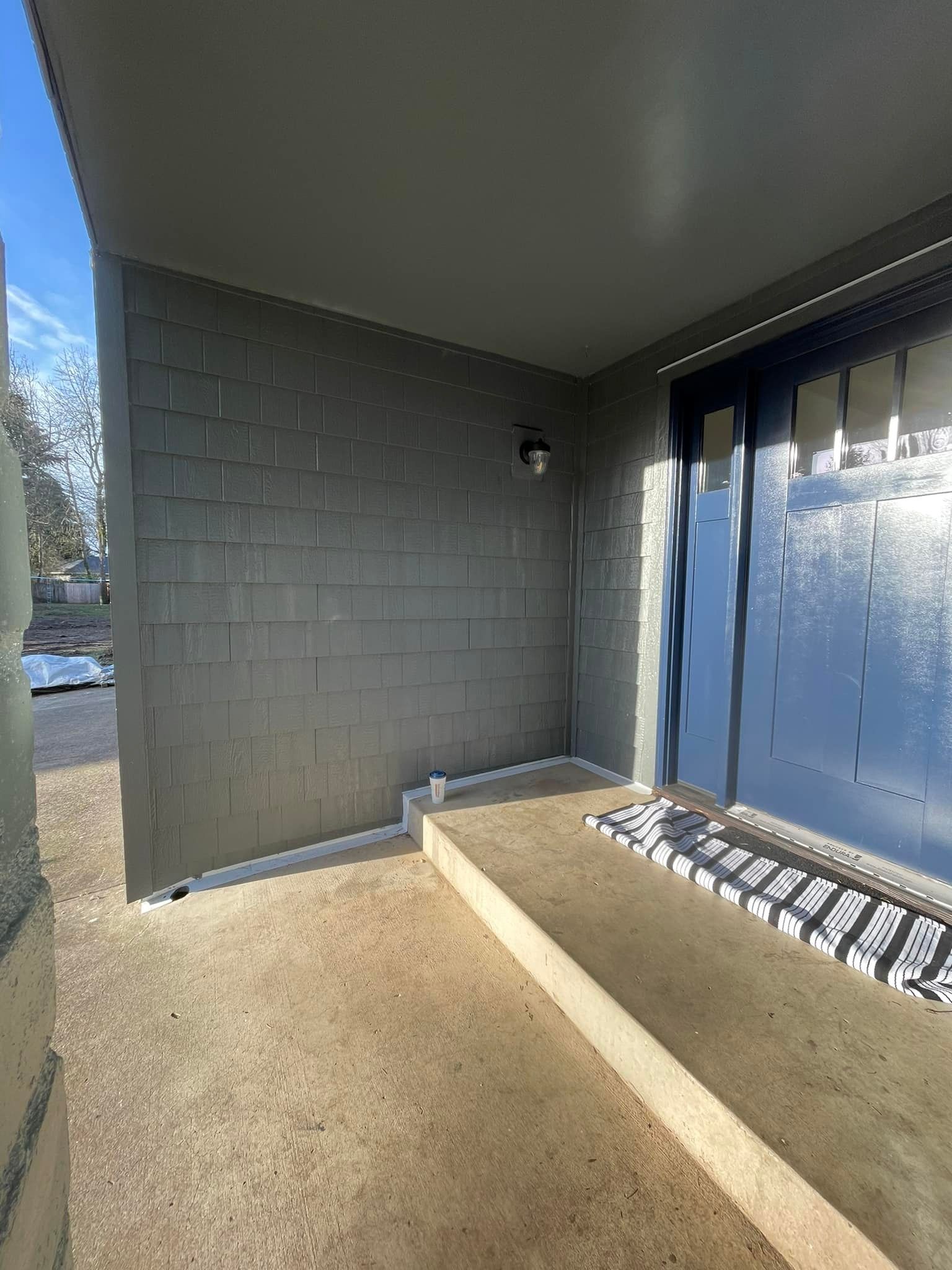 A brick building with a covered porch and a blue door.