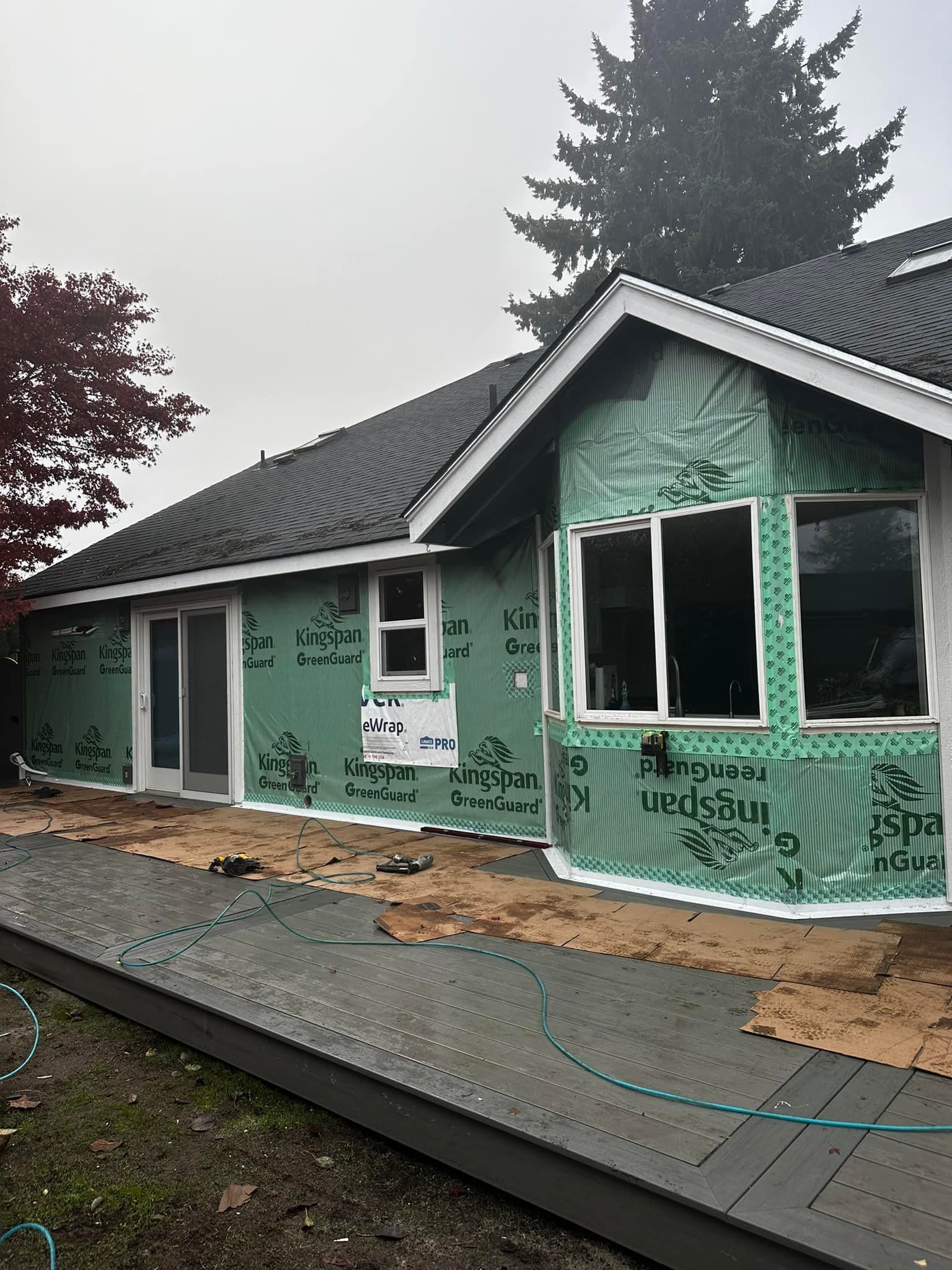 A house is being remodeled with green siding and windows.