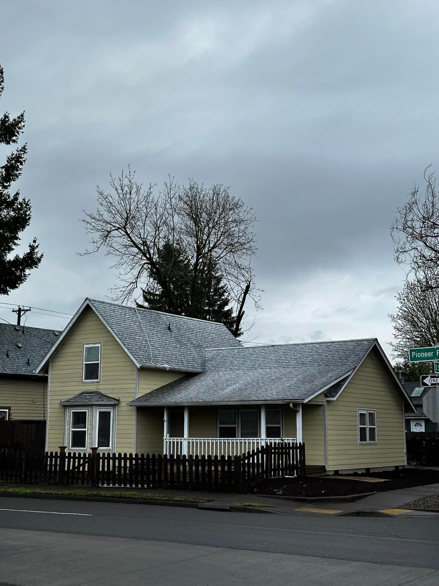 A house with a gray roof and a fence in front of it.