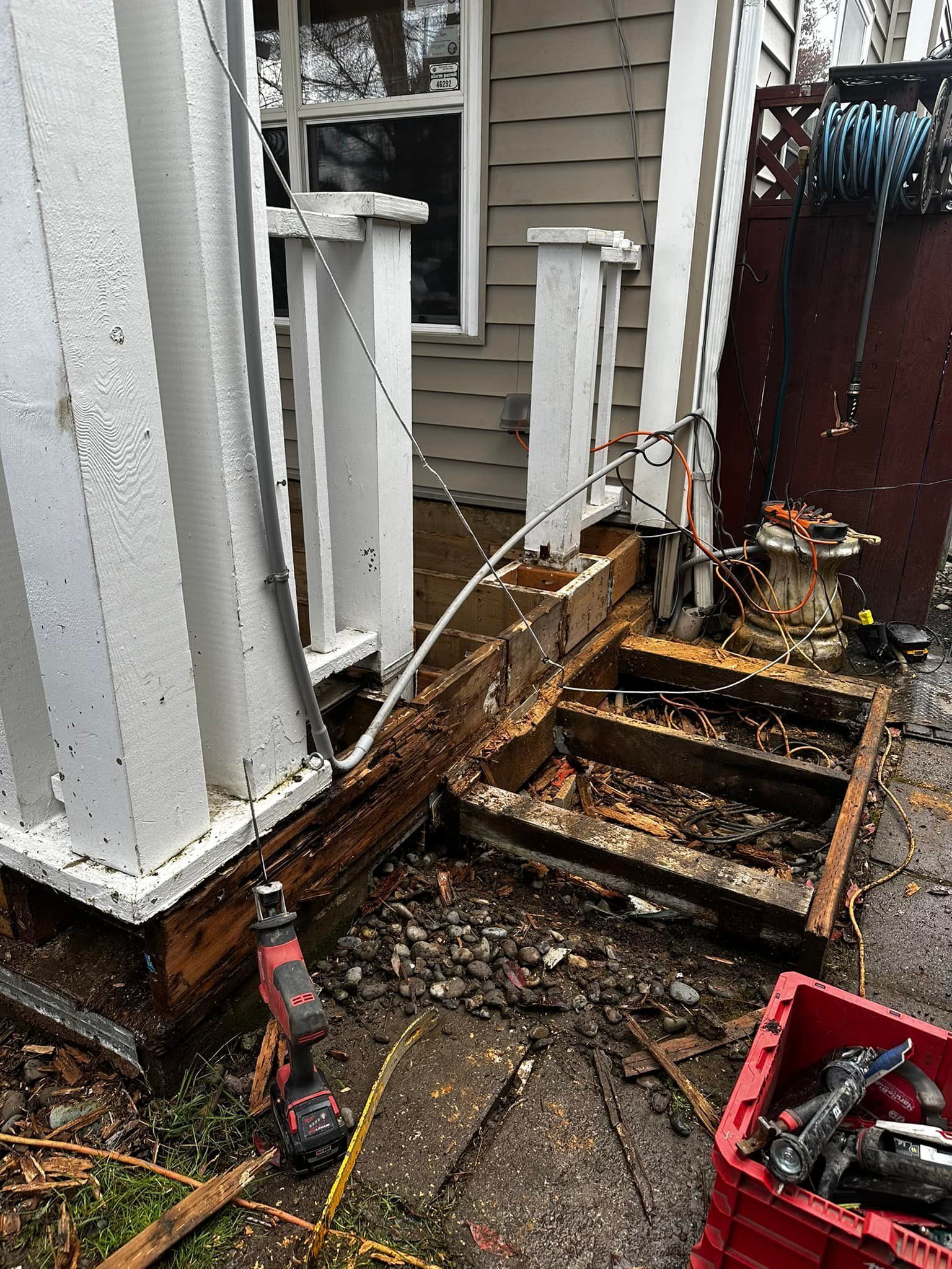 A drill is sitting next to a box of tools in front of a house.