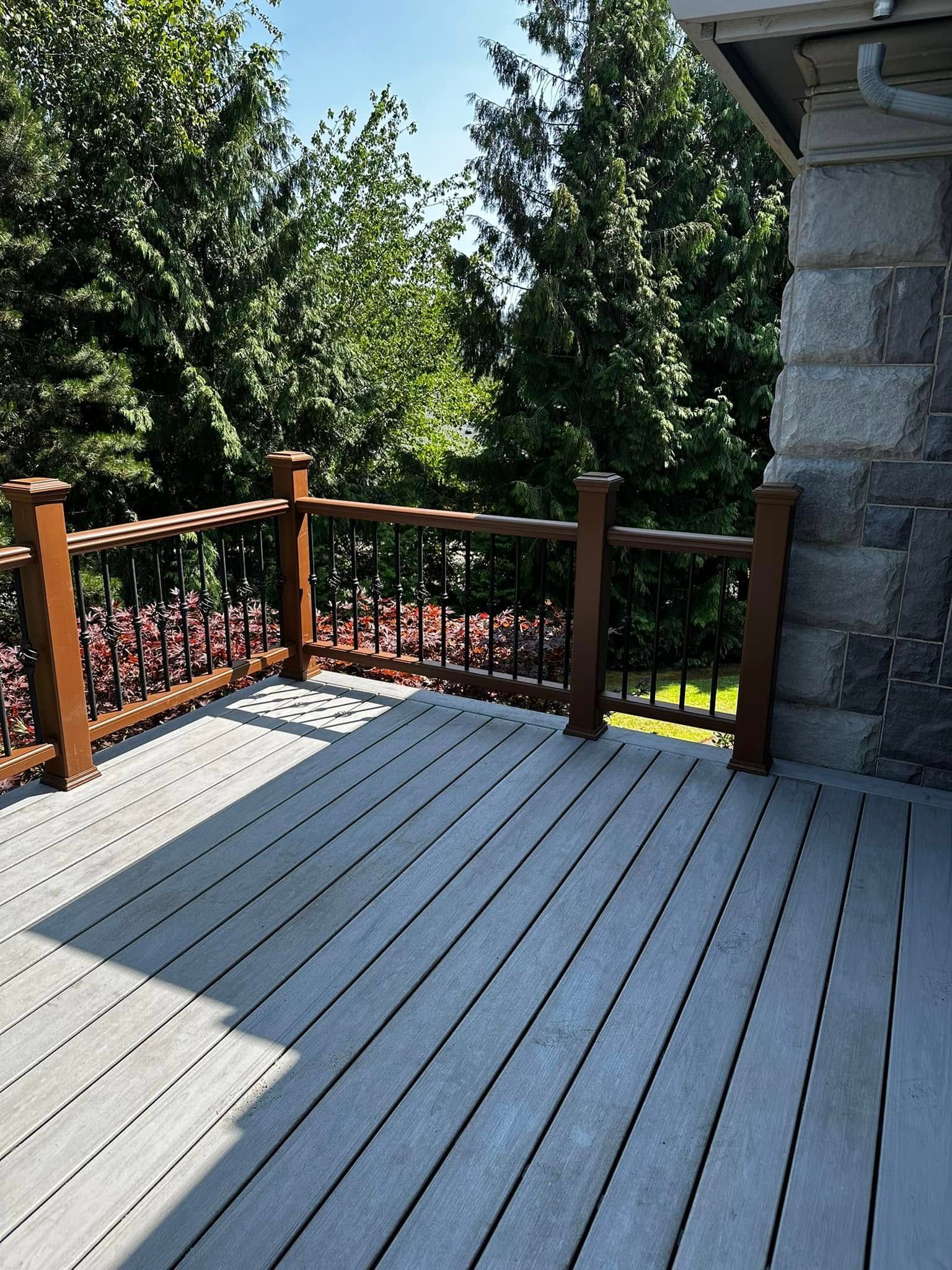 A deck with a wooden railing and trees in the background.