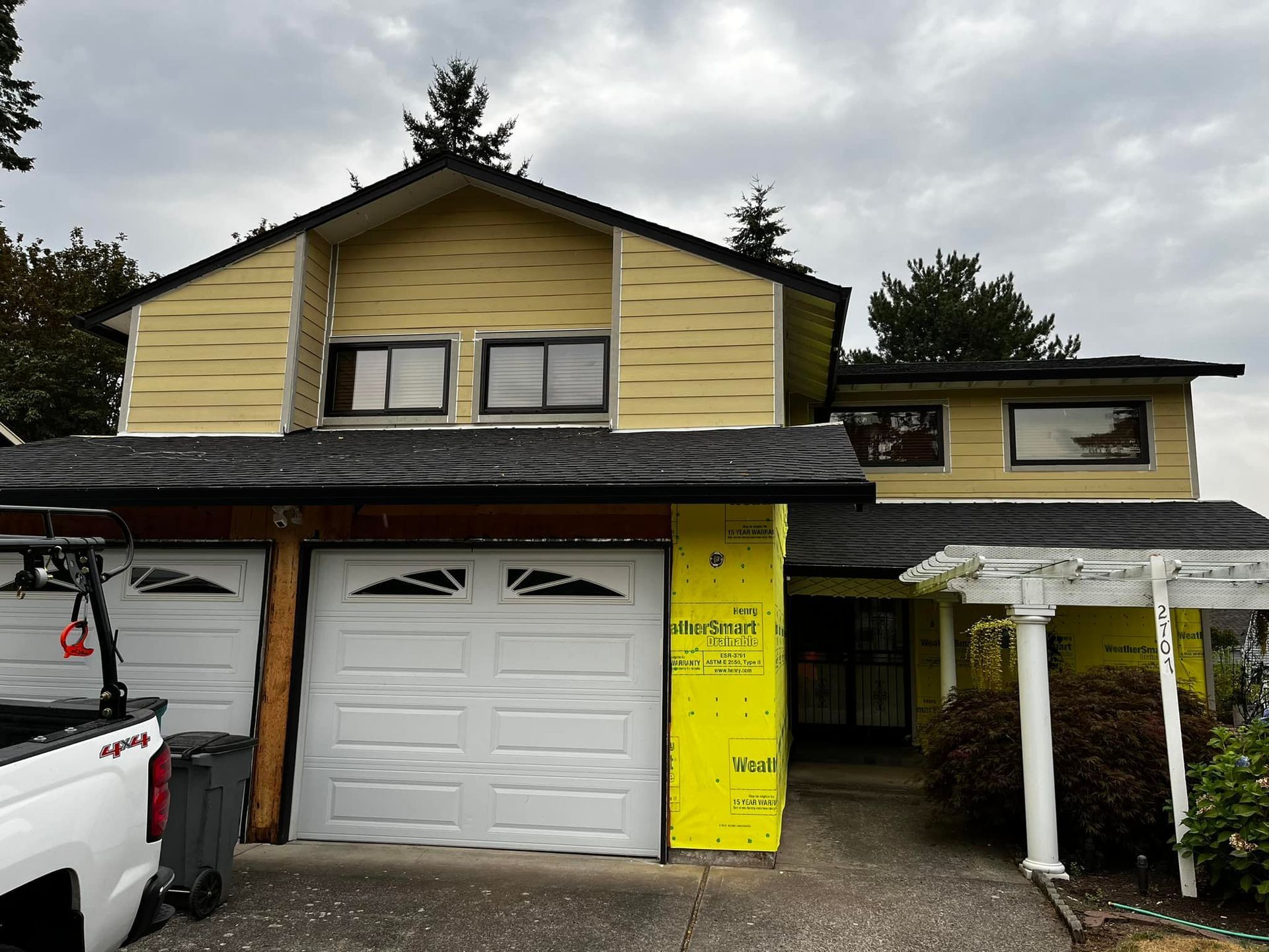 A yellow house with a white truck parked in front of it.