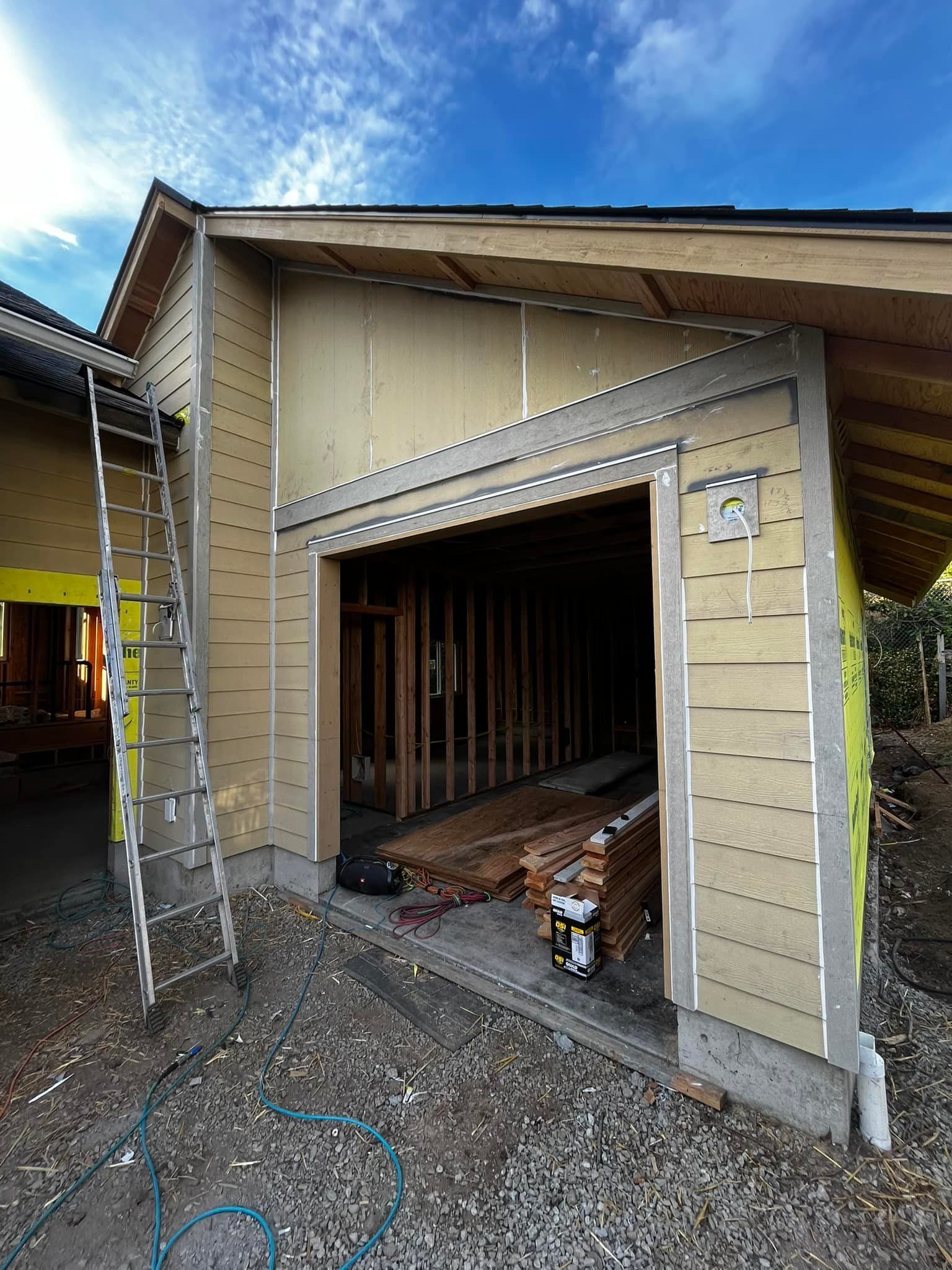 A house under construction with a garage door open and a ladder.