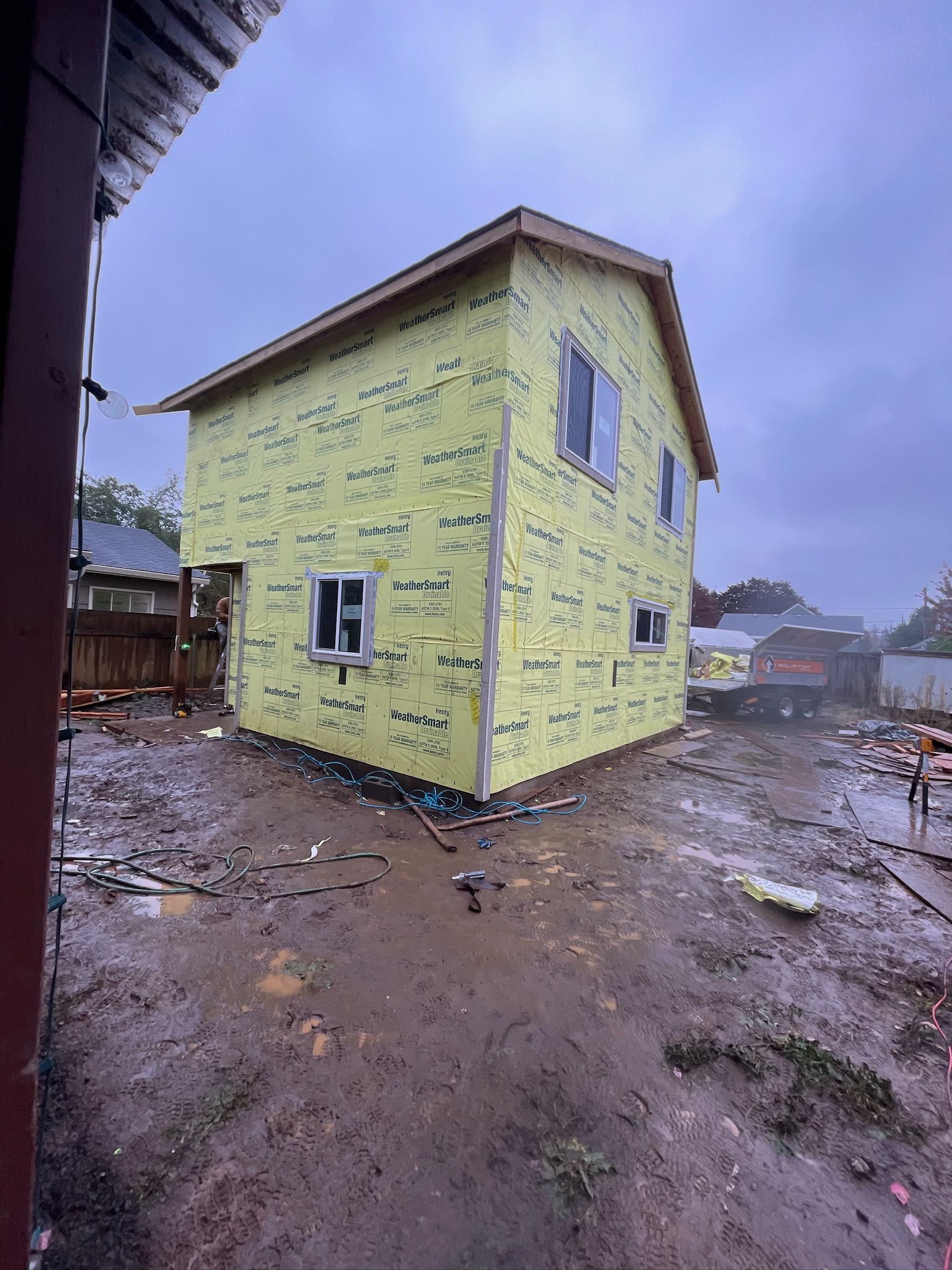 A yellow house is being built in a muddy area.