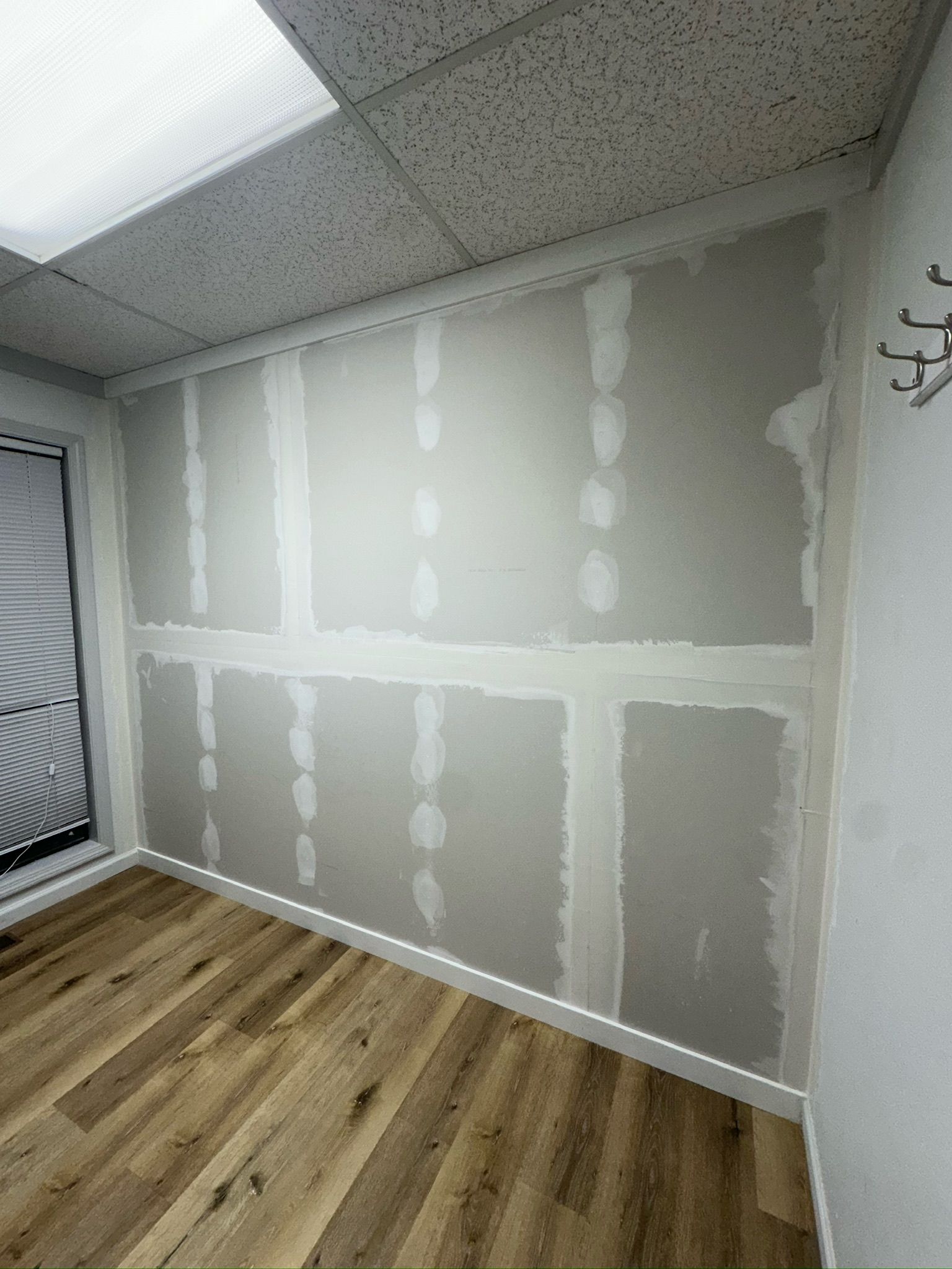 A room with a wooden floor and a drywall wall.