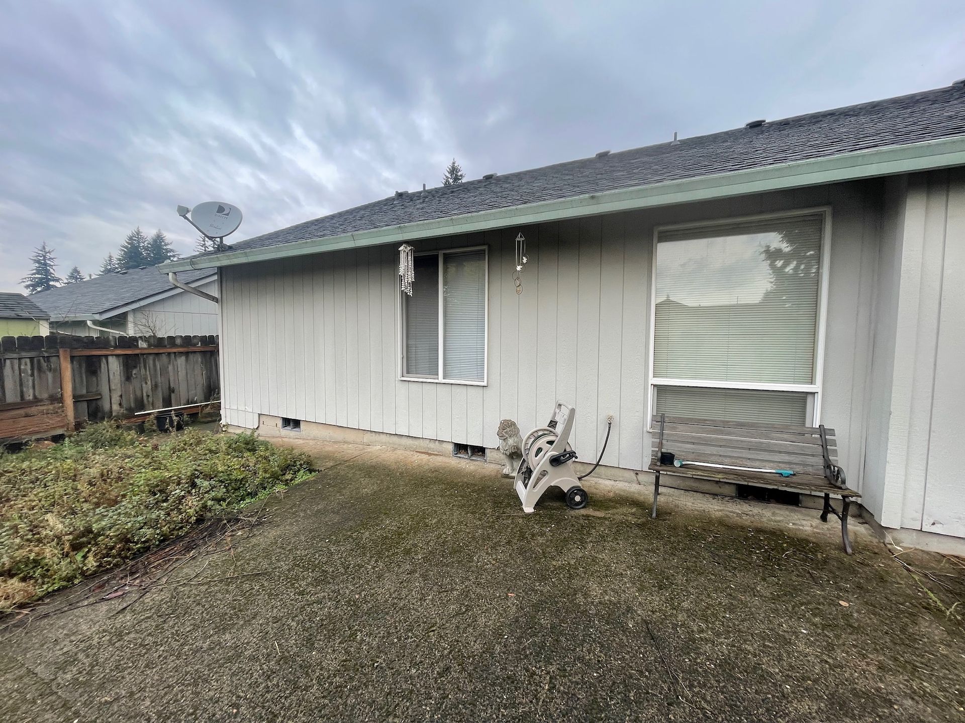 A white house with a satellite dish on the roof and a bench in front of it.