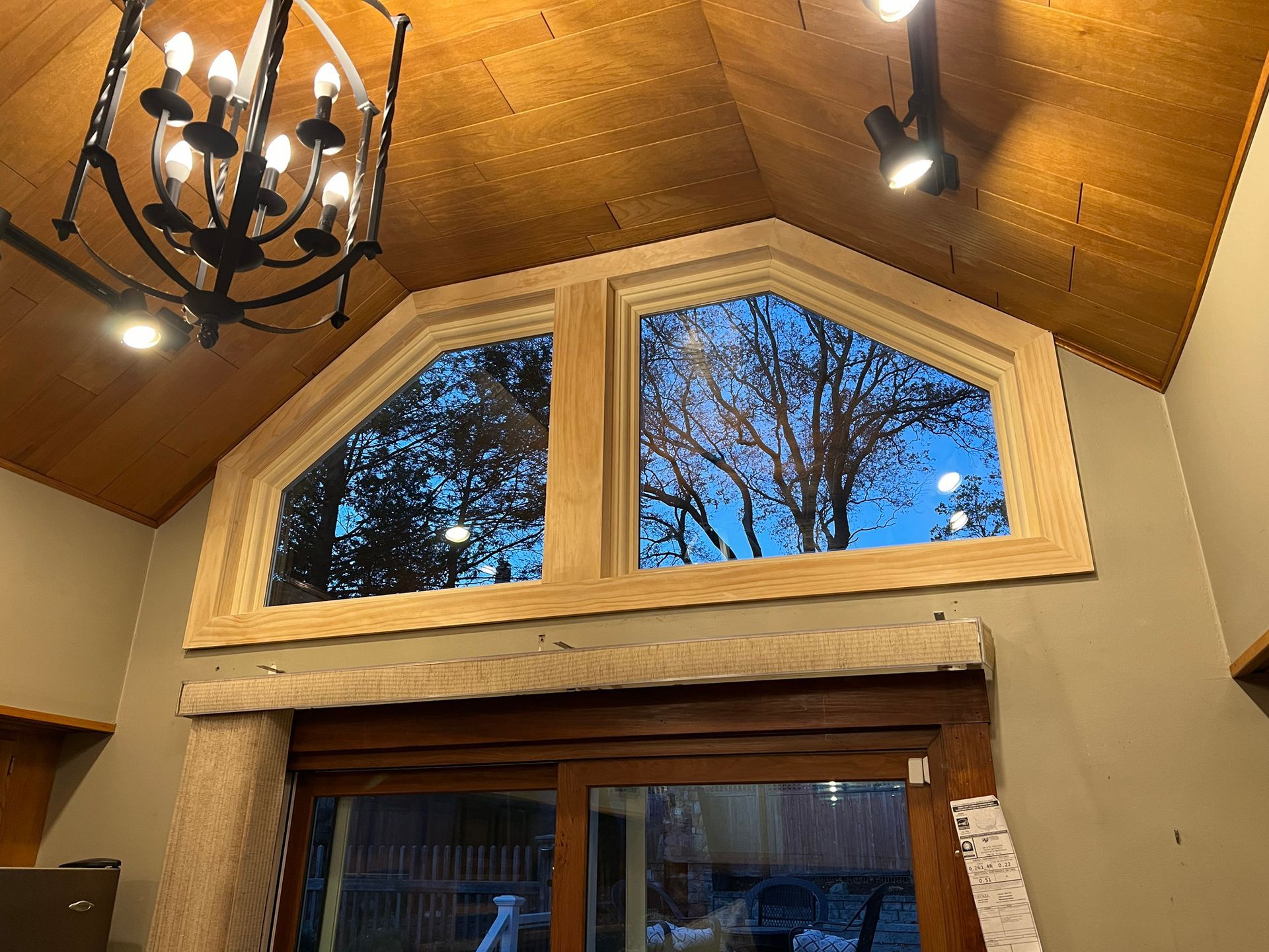 A room with a large window and a chandelier hanging from the ceiling.