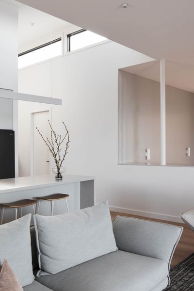 Modern white interior with a gray sofa, kitchen island, and decorative branches.
