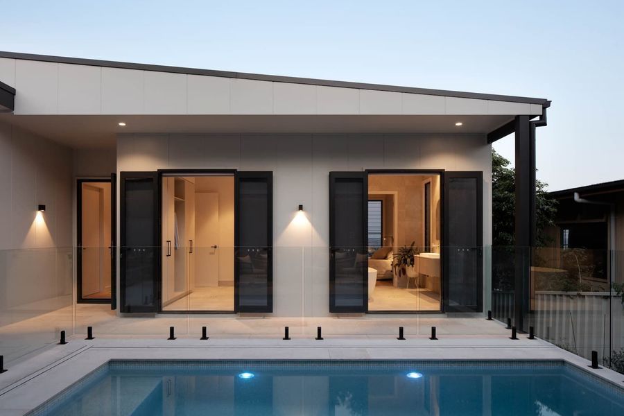 Exterior view of a modern home with pool. Open doors reveal a bathroom and closet.