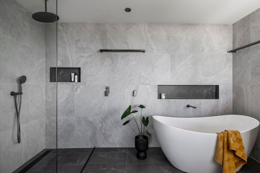Modern gray bathroom with shower, tub, and plant.