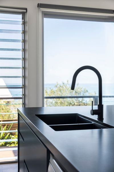 Black kitchen sink and faucet with a view of the ocean.