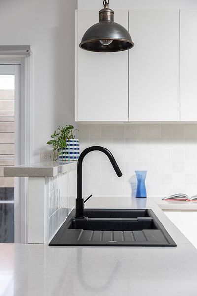 Black kitchen sink with matte black faucet and white cabinets.