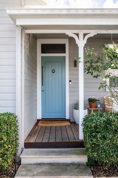 Blue front door with porch, wooden steps, and landscaping.