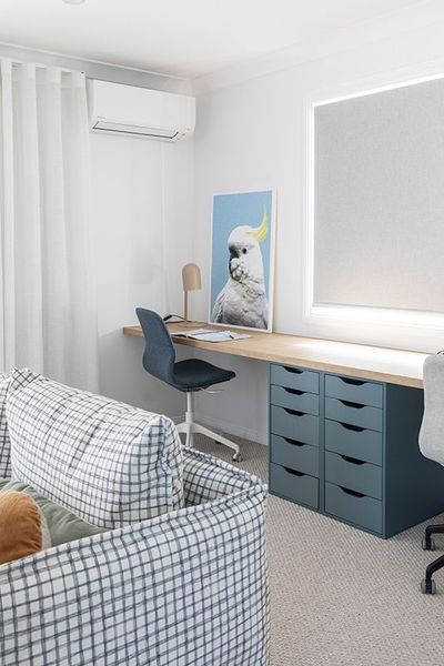 Desk with blue drawers, cockatoo art, and a checkered sofa in a home office.