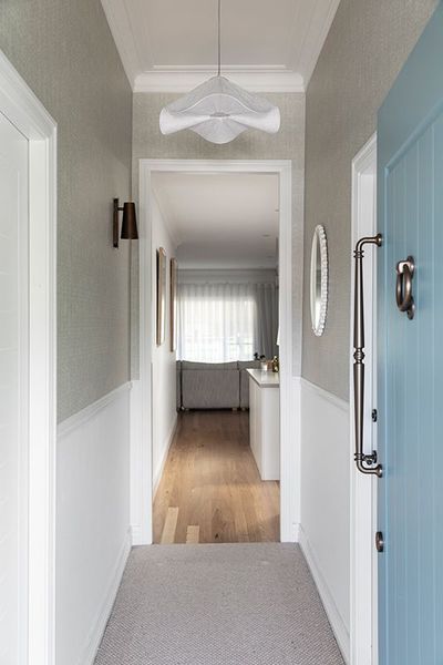 Hallway with light gray walls, white paneling, and a light blue door.