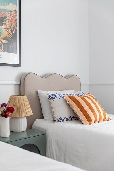 Two twin beds with a shared nightstand, neutral headboards, and decorative pillows.