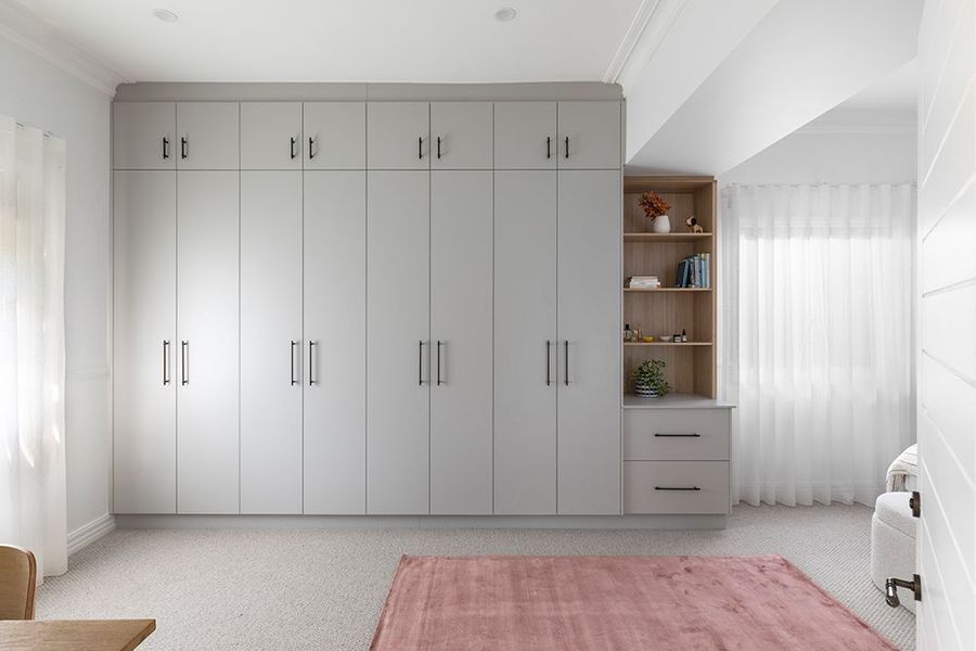 Built-in gray closet in a bright bedroom, with a pink rug.