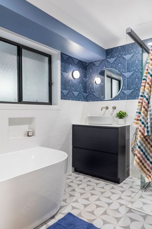 Modern bathroom with blue and white decor, dark vanity, and patterned tile floor.