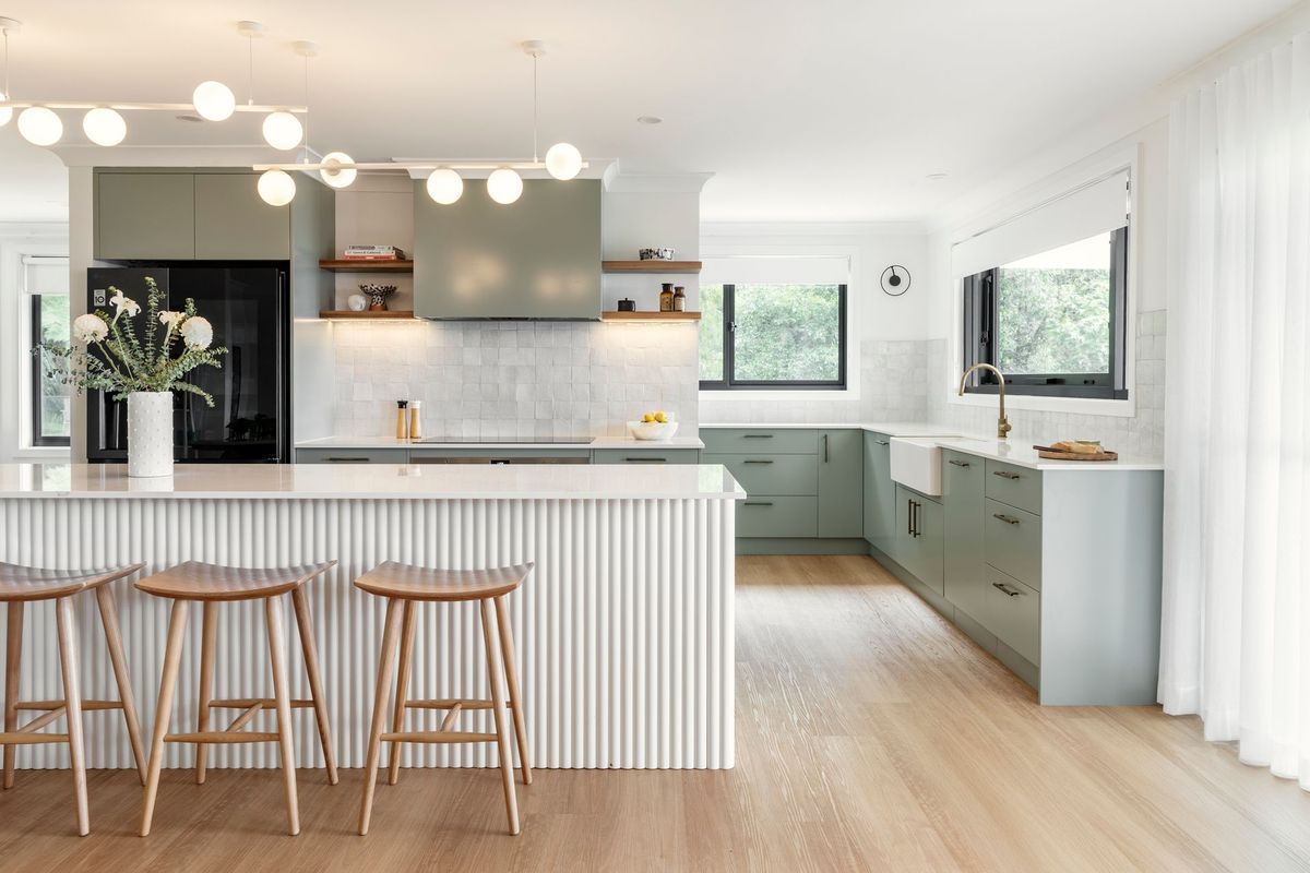 Modern kitchen with a light green color scheme and wood accents.