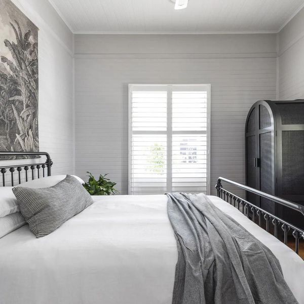 Bedroom with white bedding, gray throw, black bed frame, and a black wardrobe.