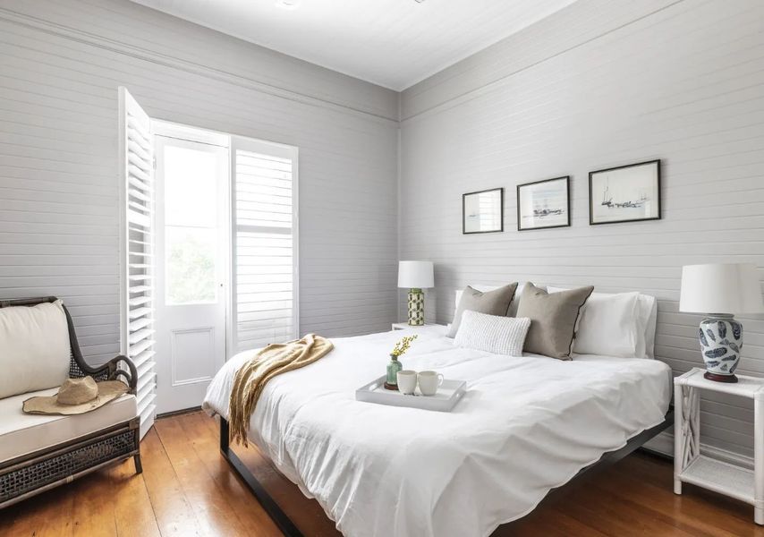 Bedroom with white bedding, shutters, and decor.