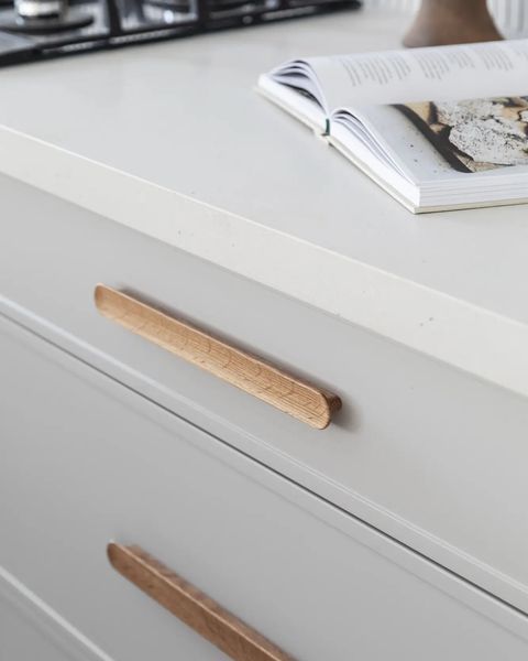 Light gray kitchen cabinets with light wooden drawer pulls, open cookbook on countertop.