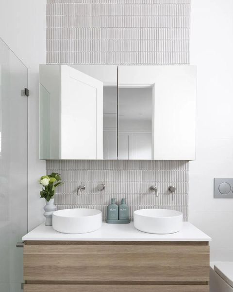 Modern bathroom with double sinks, mirrored cabinet, and wood-toned vanity. White, grey, and natural colors.