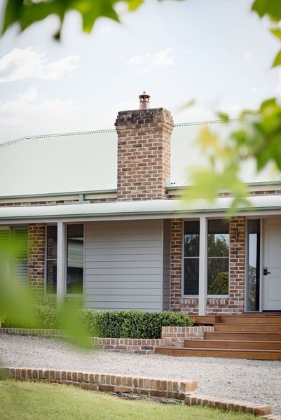 A light gray house with a brick chimney and steps leading to the front door.
