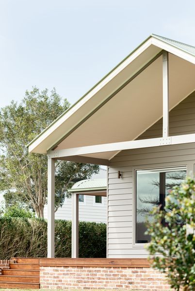 Exterior view of a modern house with a gabled roof and a wooden porch.