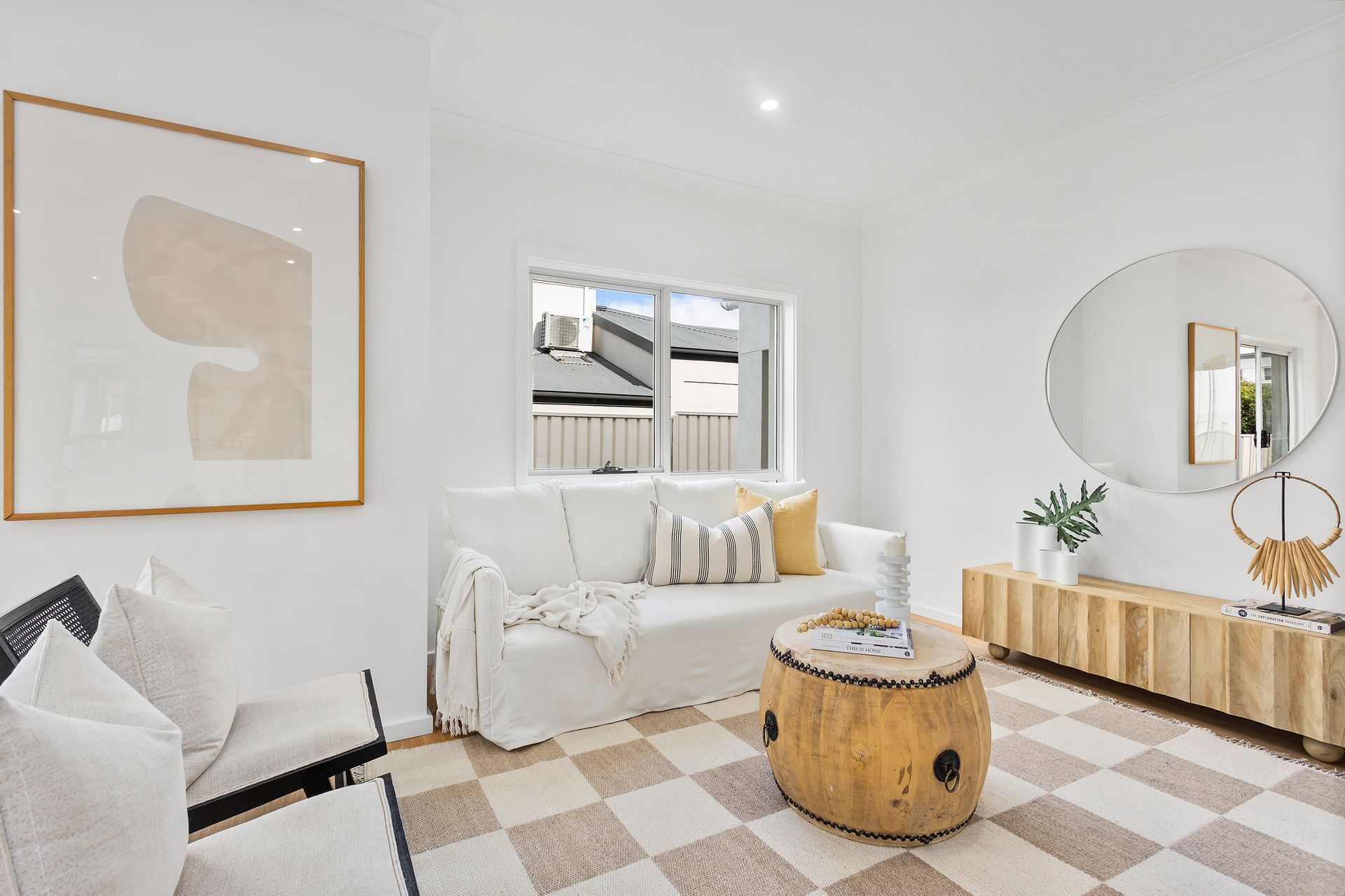 Living room with white walls, sofa, chair, and wood accents; rug with checkered pattern.