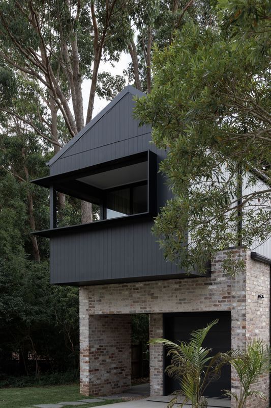 Modern house with a black, cantilevered upper level over a brick facade.