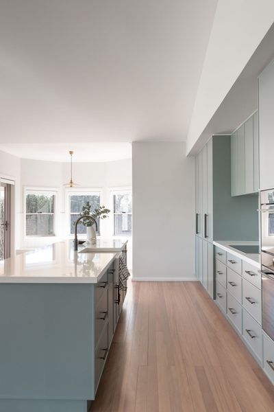 Modern kitchen with blue island and cabinets, light wood floor, and white countertops.