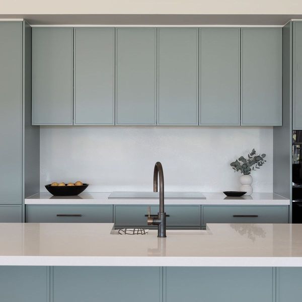 Modern kitchen with light blue cabinets, white countertop, and dark faucet.
