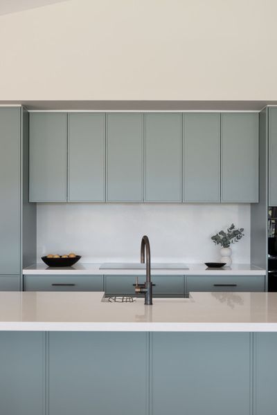 Modern kitchen with teal cabinets, white countertops, and a silver faucet.