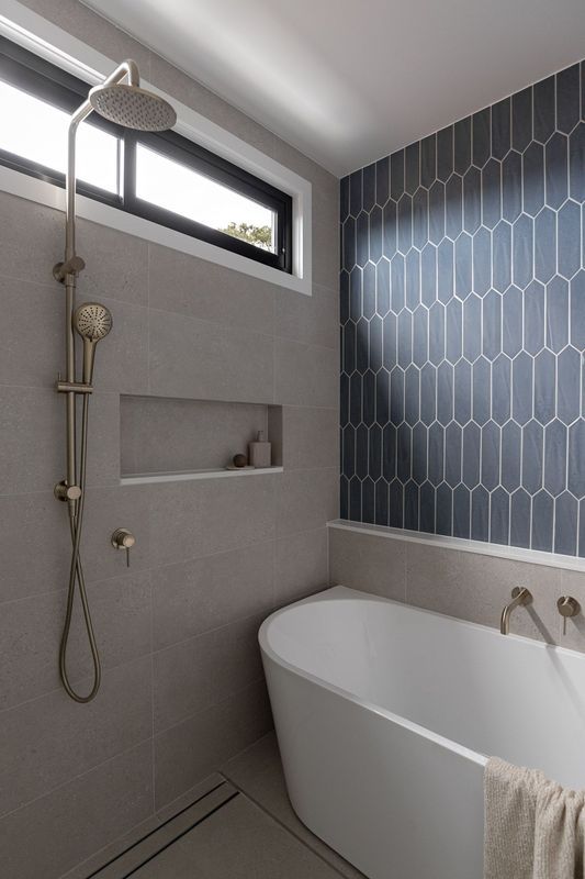 Modern bathroom with a freestanding tub, gray walls, and blue patterned tile.