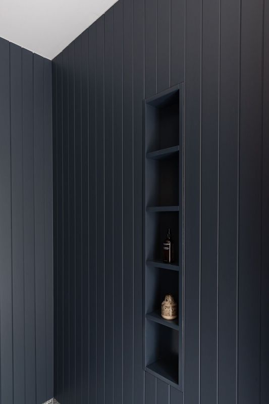 Navy blue vertical paneled wall with built-in alcove shelving.