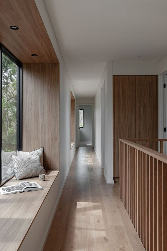 Hallway with a wooden window seat, wood floors, and a wooden handrail.